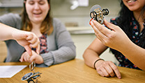 two women studying and experimenting with small physics mechanisms