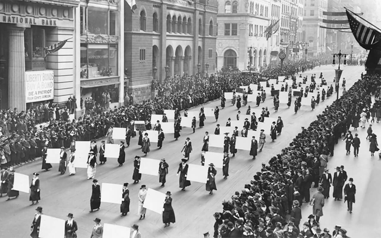 An image showing women walking on a street with big signs