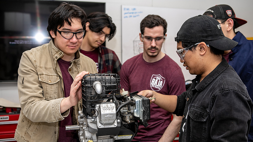 Baja racing club members work on an engine