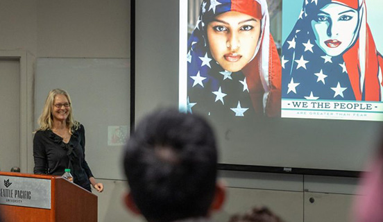 Professor Kimberly Segall presents on her book Superheroes in the Streets, displaying a photo of a women in a stars-and-stripes hijab