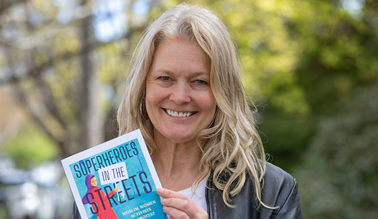 Professor Kimberly Wedeven Segall poses with her book Superheroes in the Streets