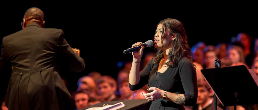 woman sings with choir in background