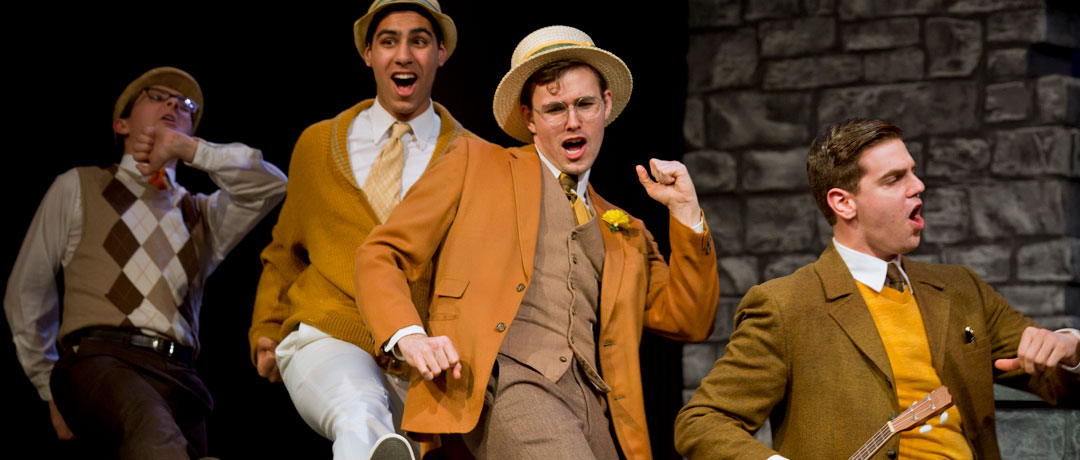 four male students performing theater on stage