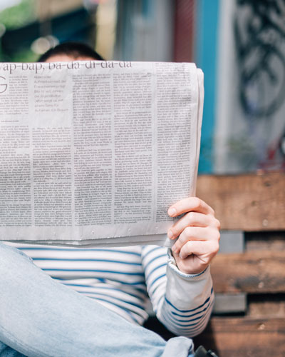 person reads newspaper on a bench