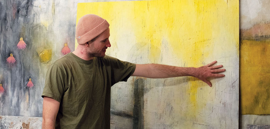 Dominic Renz stands in front of one of his paintings