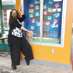 Tobi Nussbaum poses in front of a Hispanic Heritage Month display