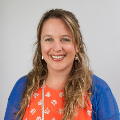 Headshot of Kirsten Koetje long blonde hair with orange shirt and blue sweater