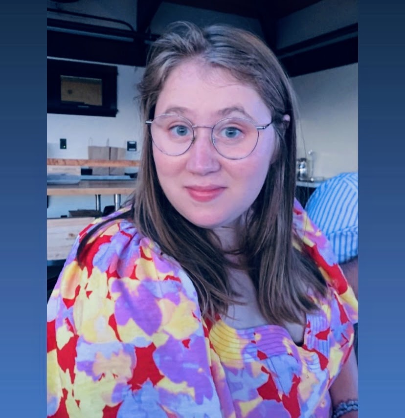 headshot of Olivia wearing a purple, yellow, red flowered shirt