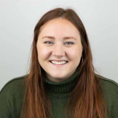 headshot of a woman with long brown hair wearing a green sweater 