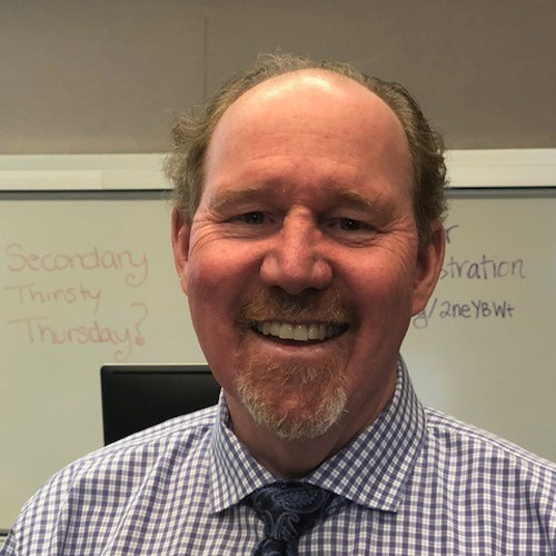 headshot of jim dunnigan wearing striped shirt and tie