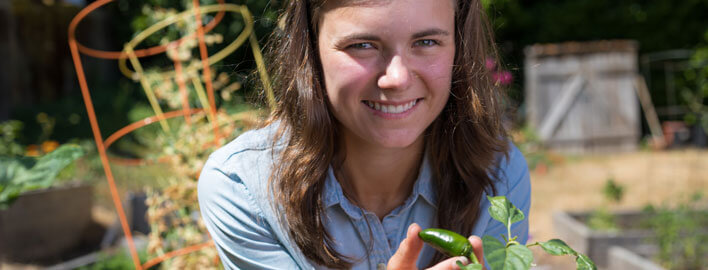 girl smiles with pepper plant