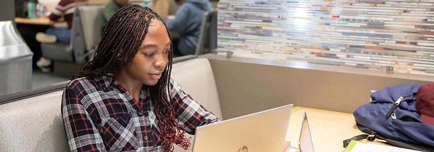 An SPU student works on their laptop in the commuter lounge on campus