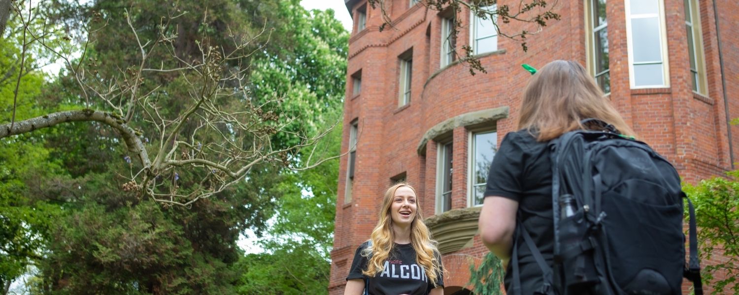 Two students stand just outside Alexander and Adelaide Hall 