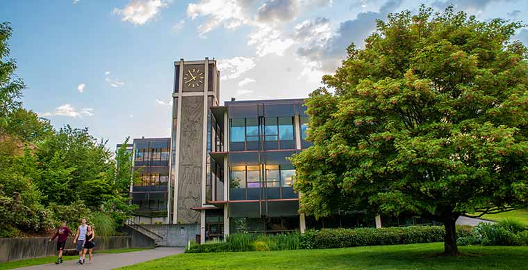 A shot of Demaray Hall on Campus, with a few student walking in front of it