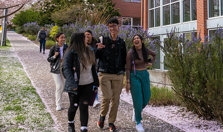 Students walk through the cherry blossoms outside Emerson Hall